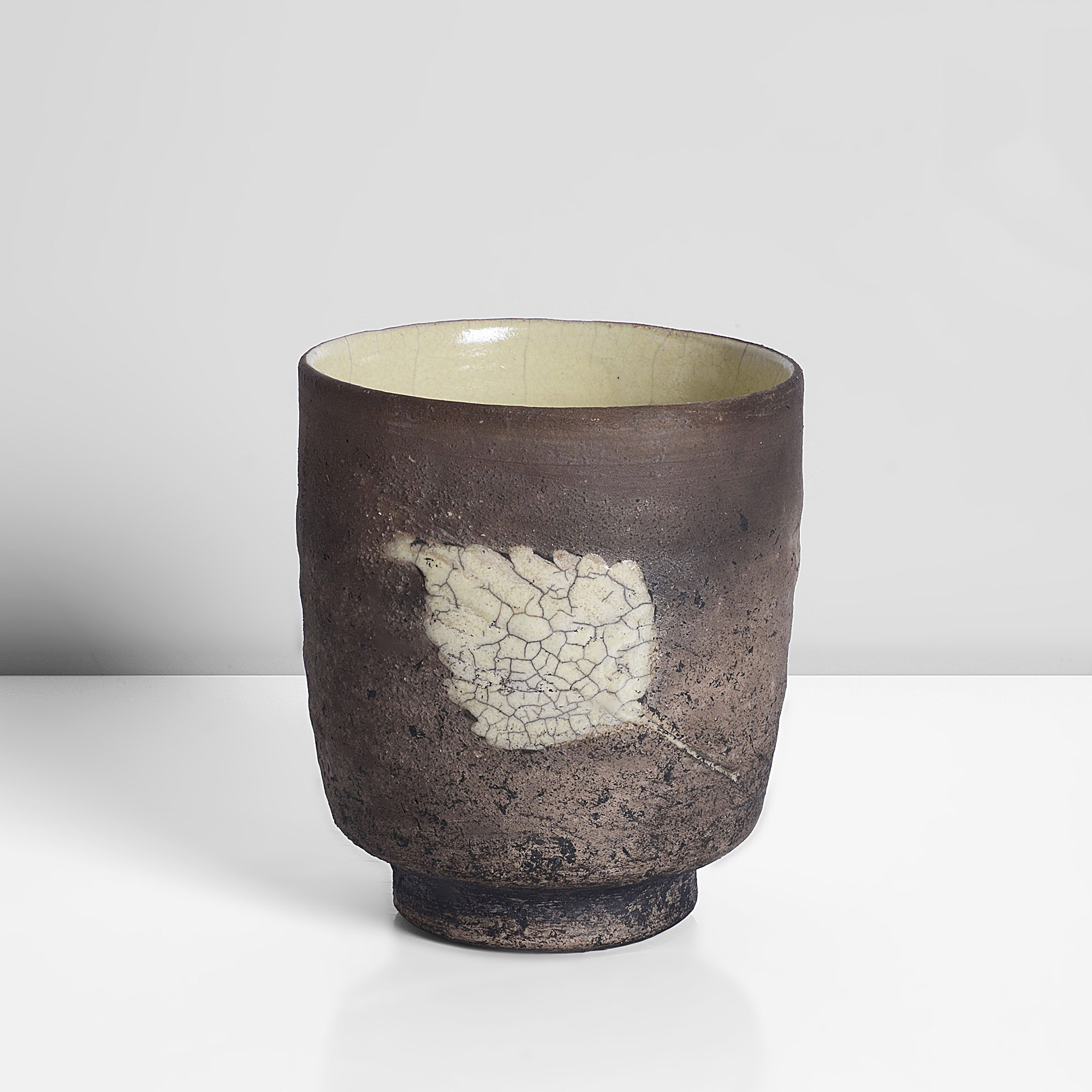 Earthenware, Ceramic raku fired dry brown body with a pale yellow and grey crackle glazed leaf motif, the interior with a pale yellow glaze with soft grey crackle, impressed IR seal