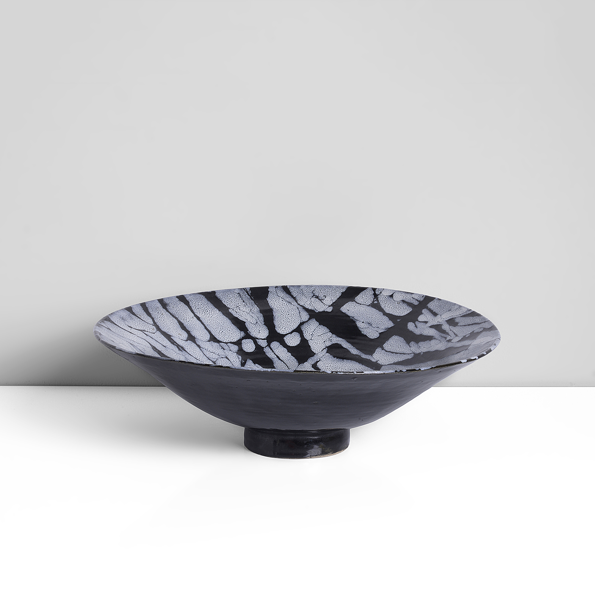 Earthenware, black and white marbled tin glaze to the well, black tin glaze to the exterior, incised signature