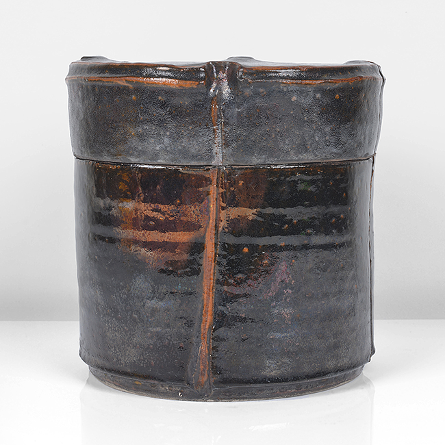 Raku, dark brown mottled glaze with lustrous copper flashes, the glaze thinning to rust red at the edges, the flat topped lid with impressed thumb prints at four points with an incised line running down the edge and down the body, impressed IR and date seals